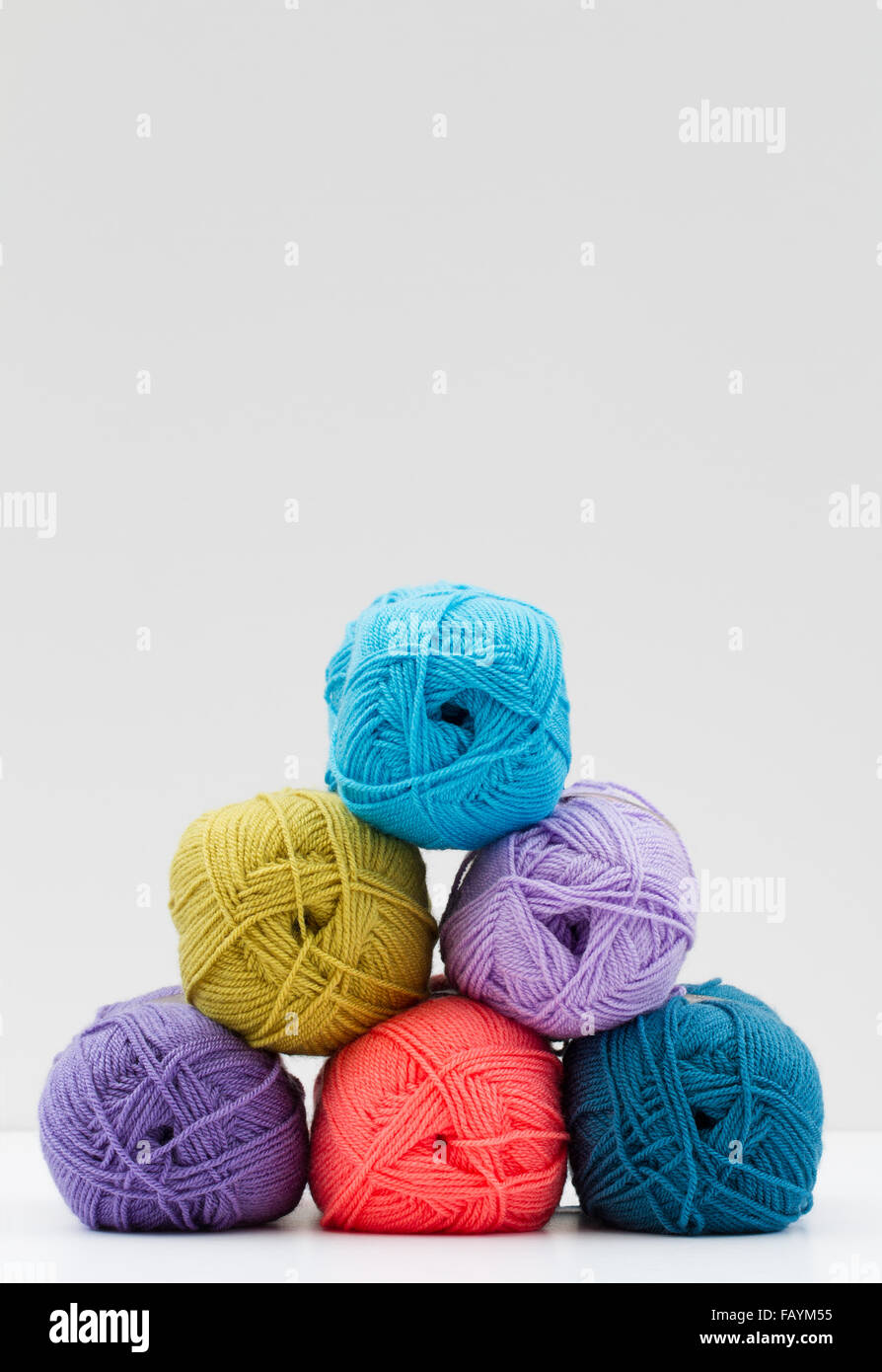 Colourful and varied balls  of wool or yarn  stacked up against a white background. Stock Photo
