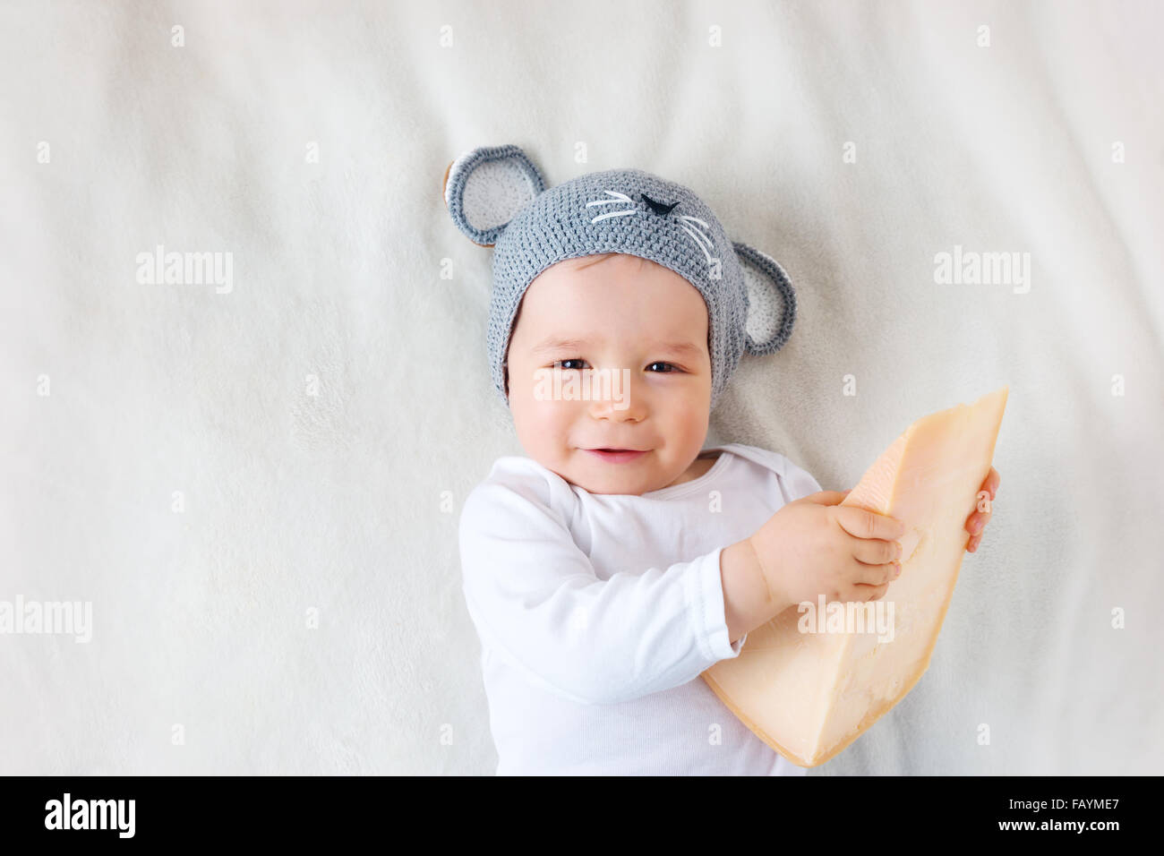 Baby boy in mouse hat lying on blanket with cheese Stock Photo
