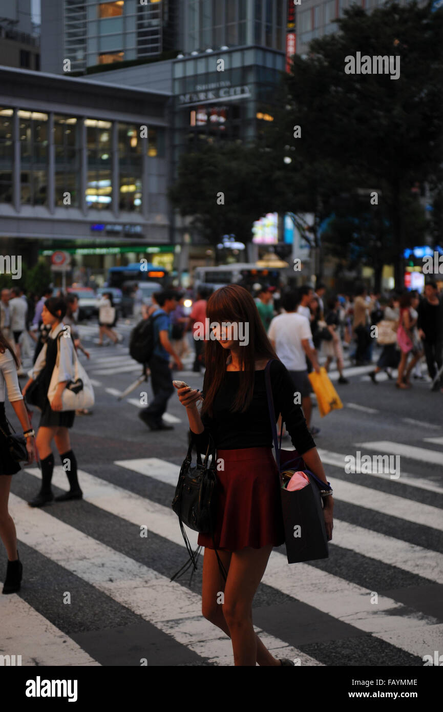 woman on pedestrian traffic light crossing looking her smart phone in Shinjuku Tokyo Japan Stock Photo
