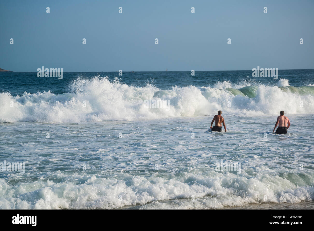Ipanema Beach, Two man in the ocean with big waves, Rio de Janeiro, Brazil Stock Photo