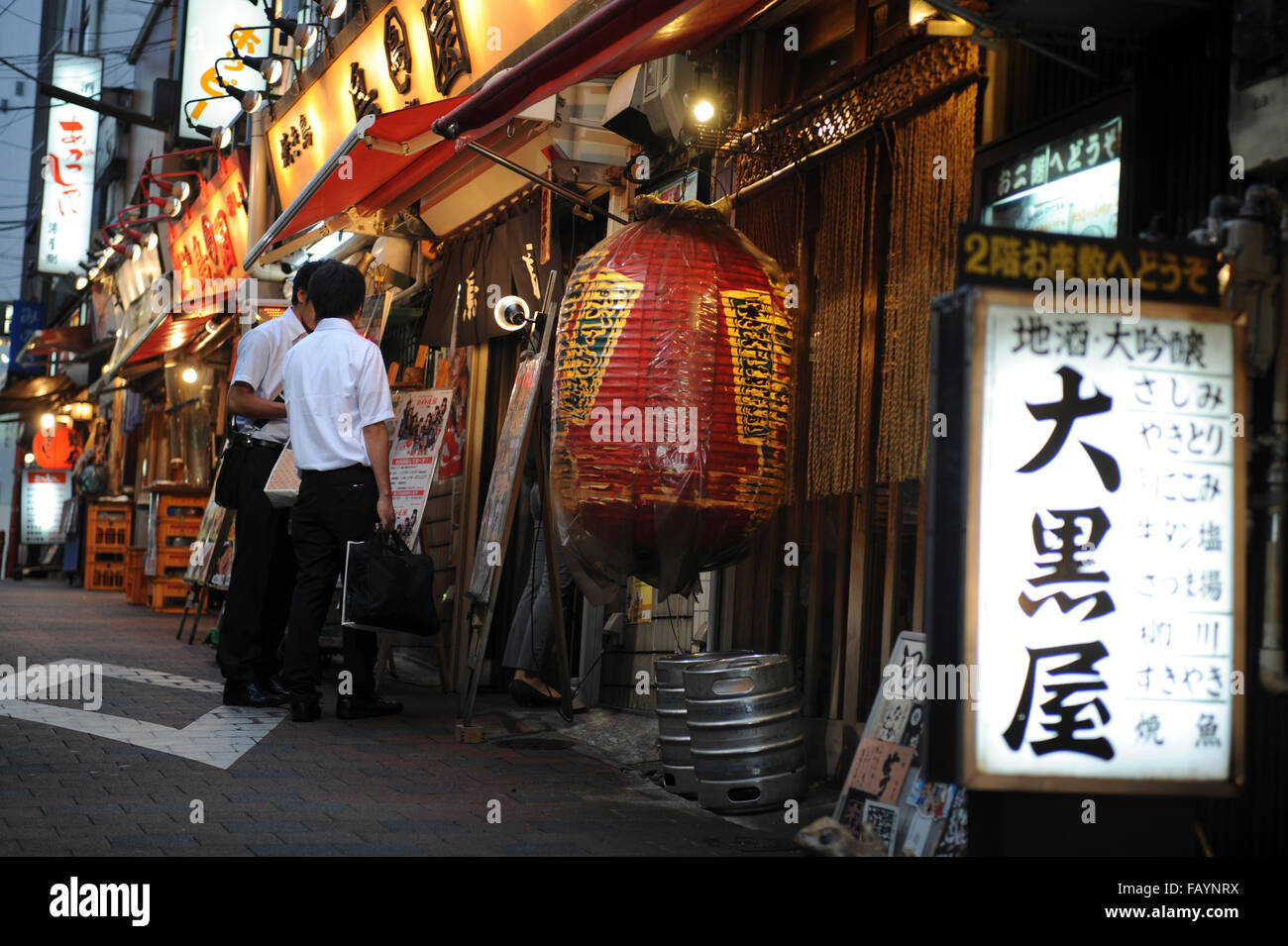 two men at the entrance of a traditional Japanese restaurant in the district of Asakusa Tokyo Japan Stock Photo