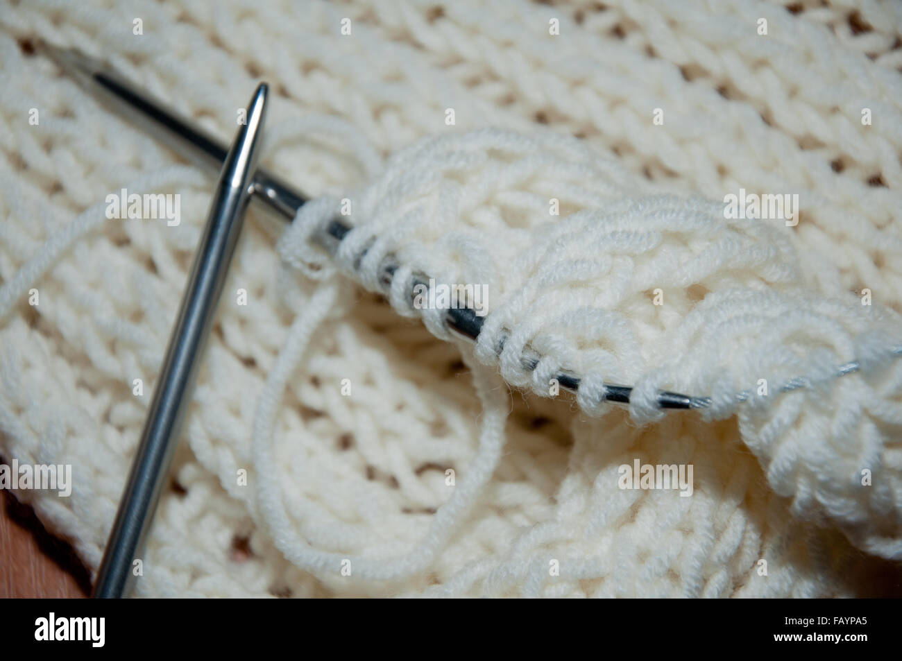White wool scarf and knitting needle. Knit work. Stock Photo