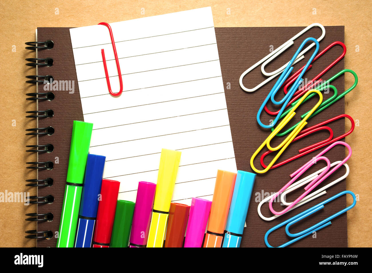 Note paper clip on notebook with colorful marker pen and paperclips on  brown cardboard background Stock Photo - Alamy