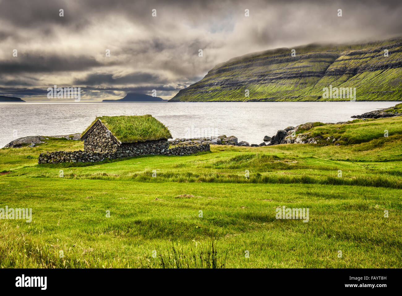 Rustic stone cabin at the edge of a lake on Faroe Islands, Denmark Stock Photo