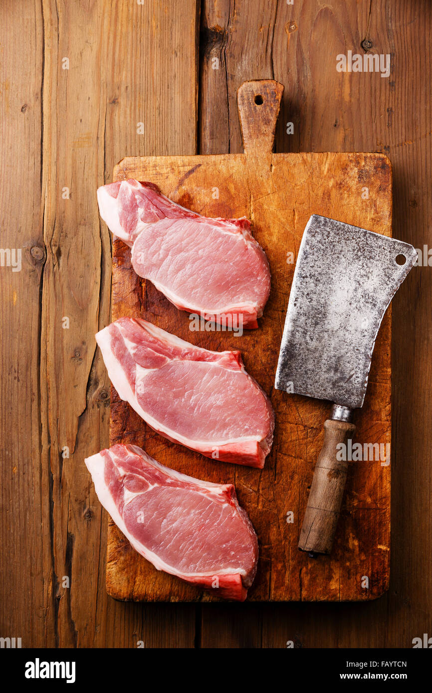 Raw fresh uncooked Pork meat steak on bone on cutting chopping board block on wooden background Stock Photo
