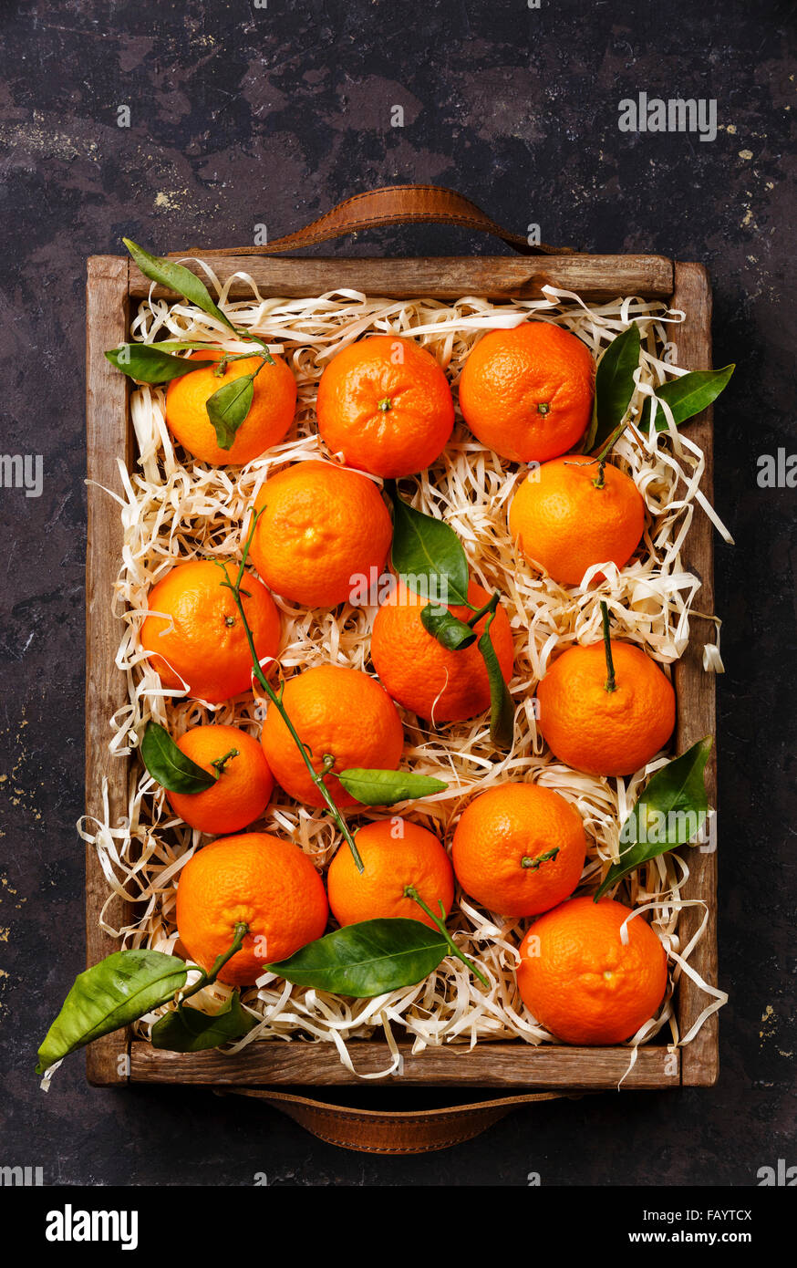 Tangerines with leaves in wooden box on black background Stock Photo