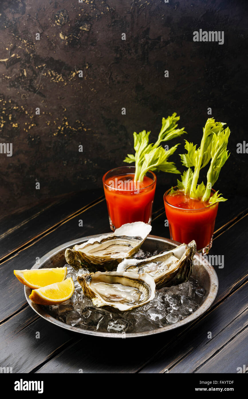 Shucked Oysters Fines de Claire and Bloody Mary cocktail on dark background Stock Photo