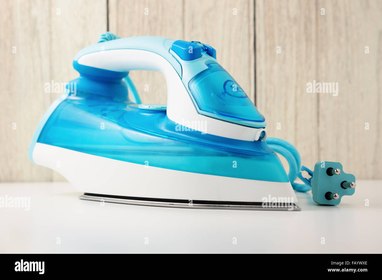 Steam iron on white table with wood wall background Stock Photo
