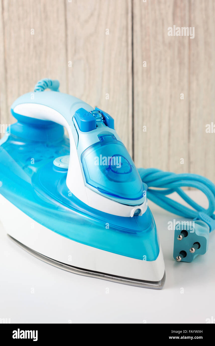 Steam iron on white table with wood wall background Stock Photo