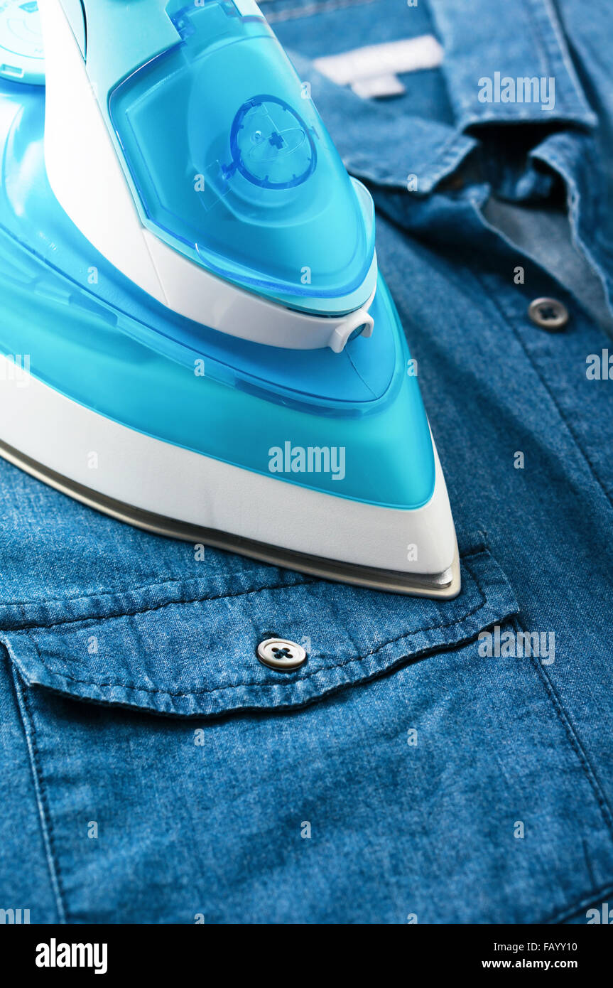Ironing blue denim shirt with steam iron Stock Photo Alamy