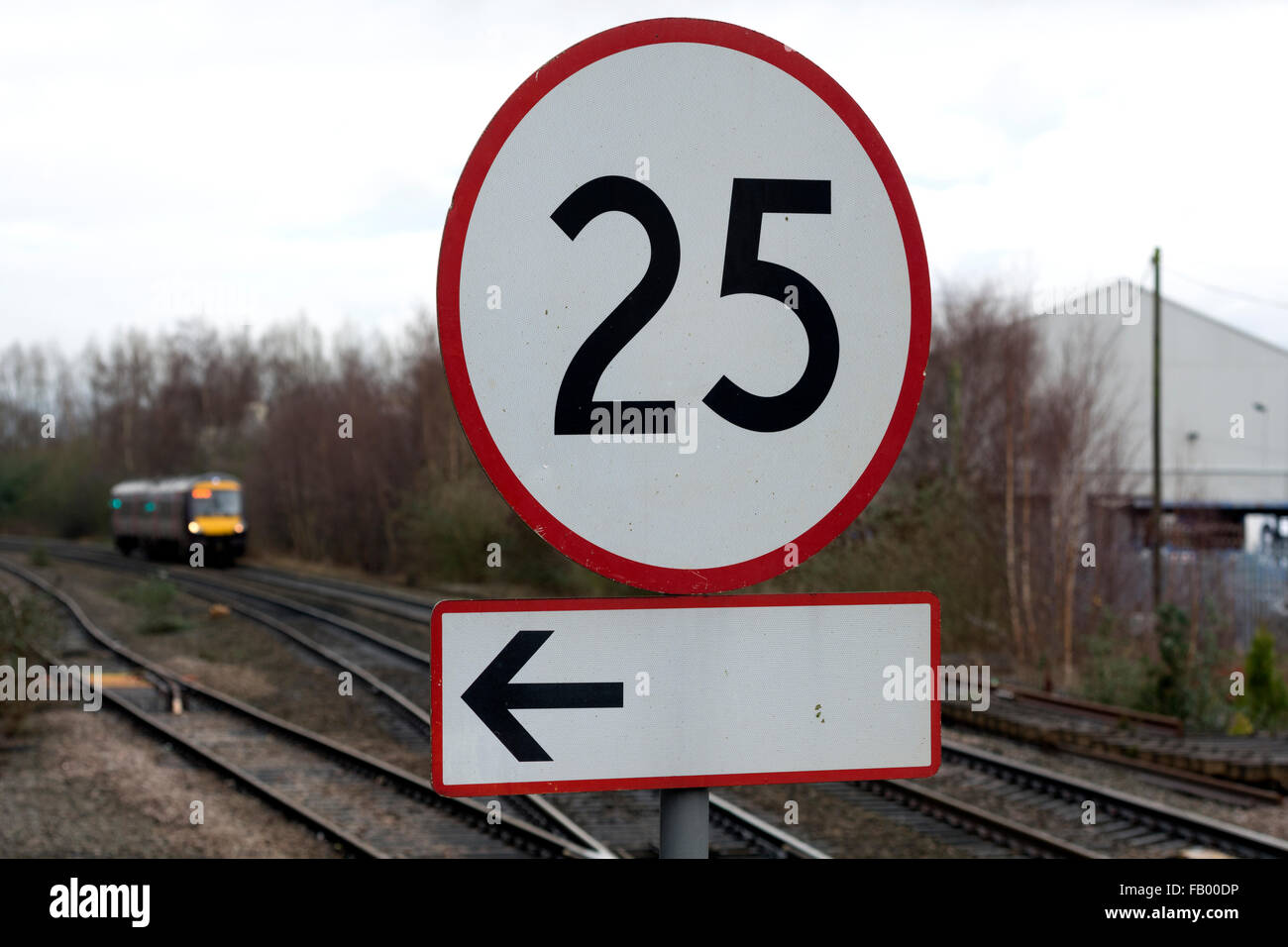 Railway sign meaning beginning of speed limit stretch at railroad  embankment with rail track disappearing in mist in background Stock Photo -  Alamy