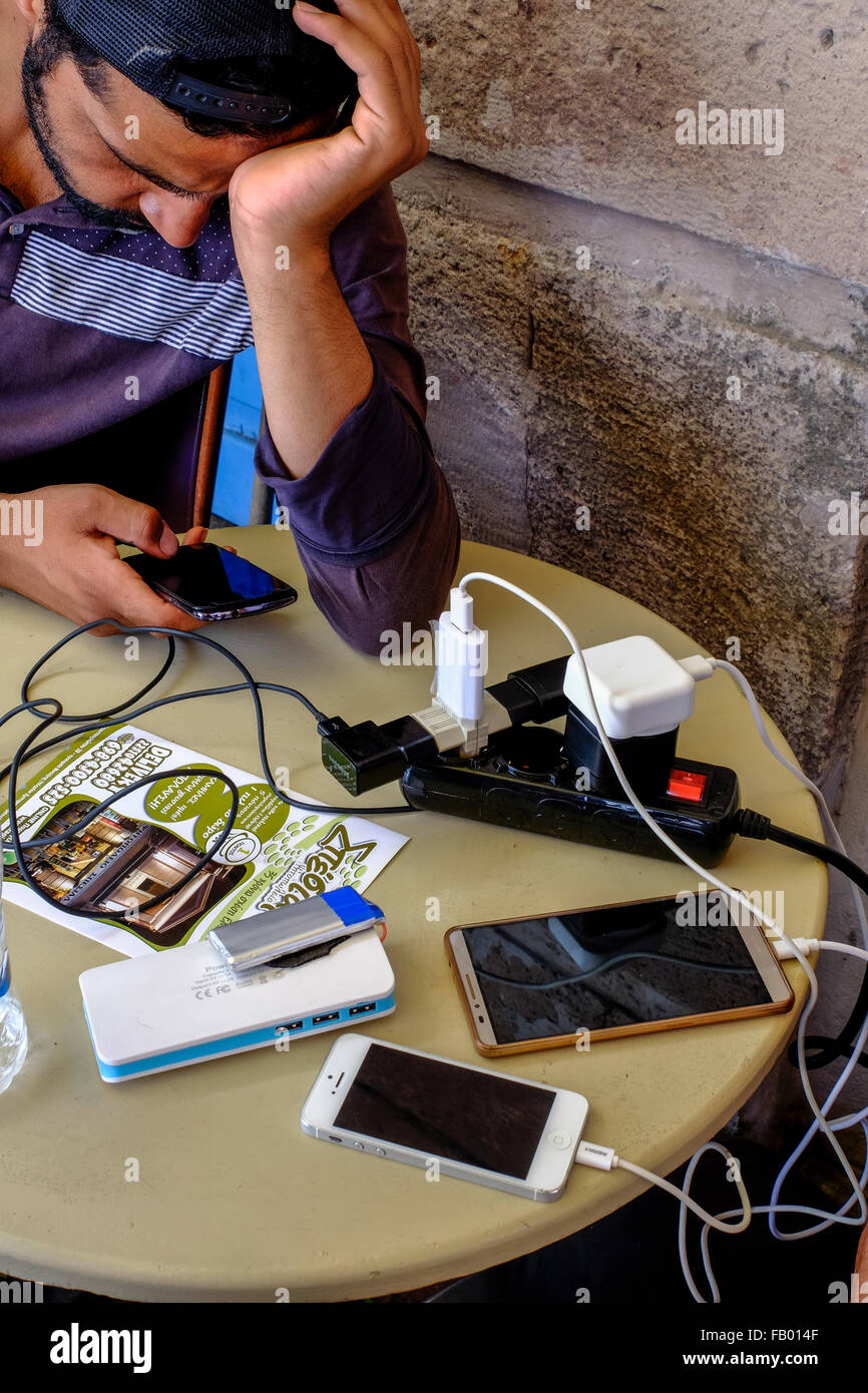 A Syrian refugee charges his mobile phone where many other refugees are recharging their