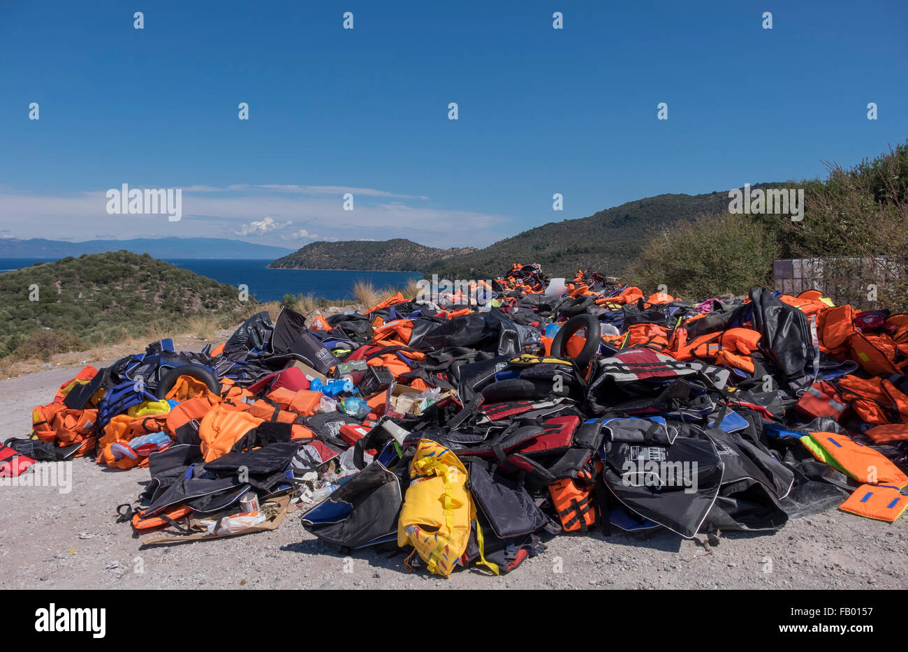 A mountain of life vests left behind by refugees crossing into the Greek island of Lesvos from Turkey (in the distance). Stock Photo