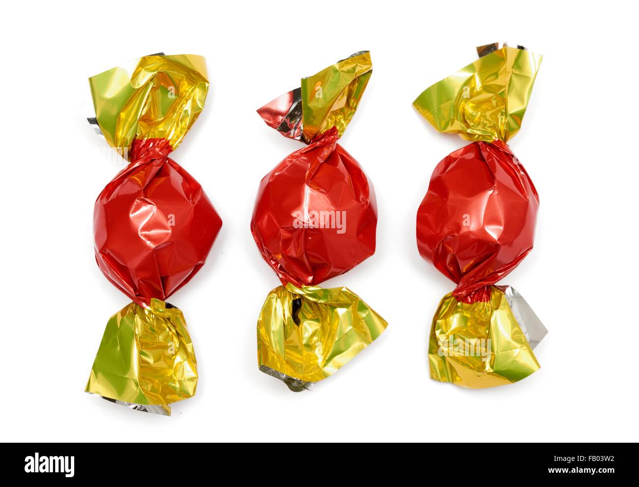 3 sweets wrapped in red and gold wrappers Stock Photo - Alamy