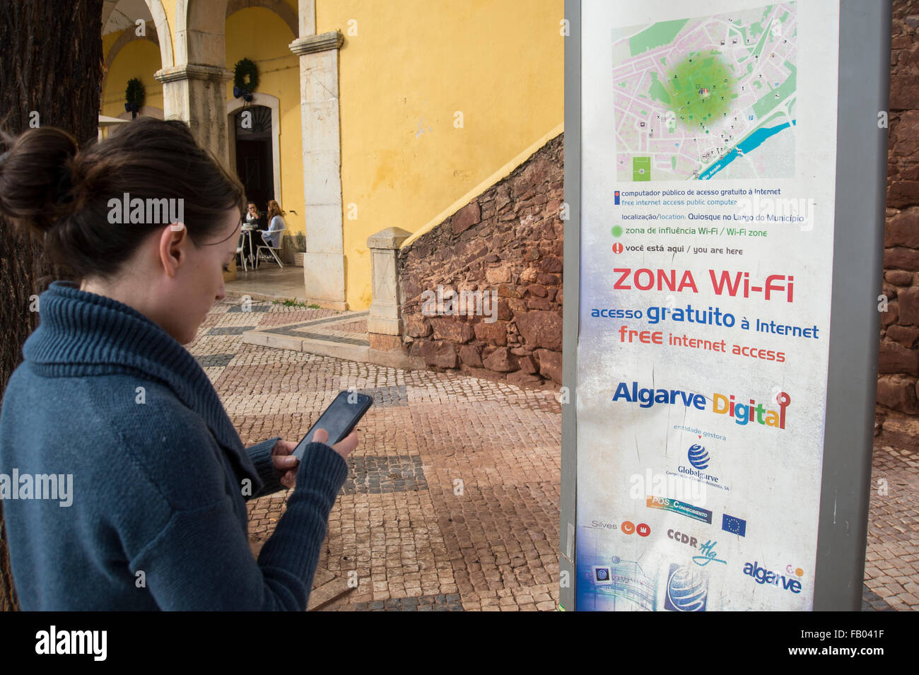 woman using her phone in the free wifi zone in Silves, Algarve, Portugal. Stock Photo