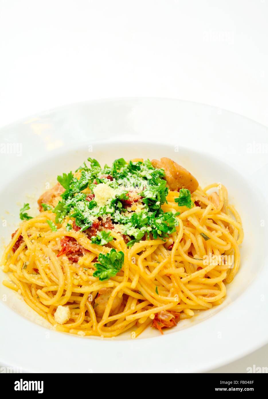 Spaghetti with sun-dried tomatoes, chicken meat, parmesan and sprinkled with parsley. Stock Photo