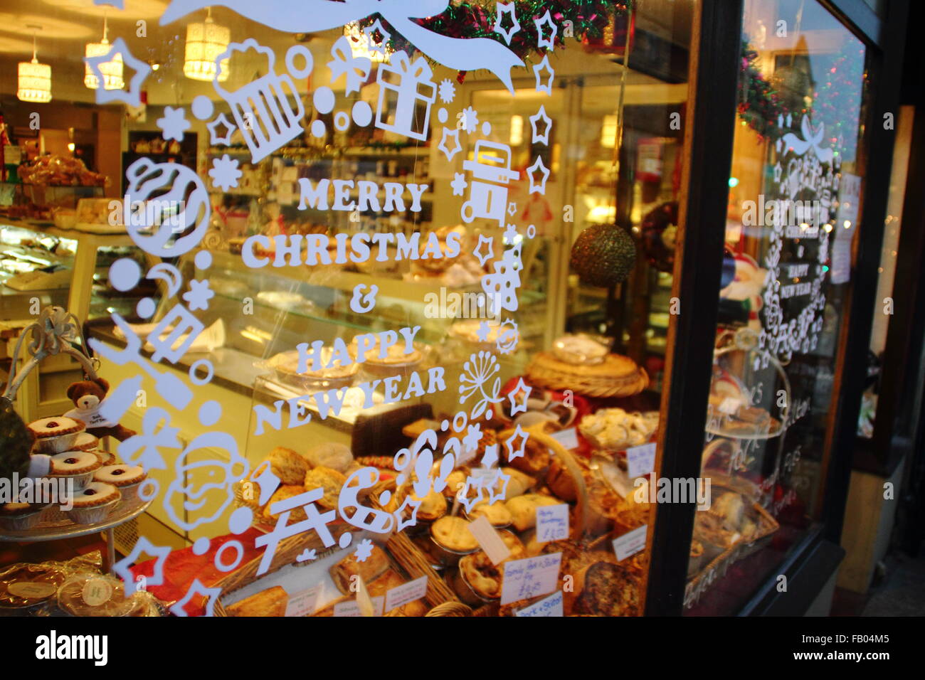 A sign wishing passers by and customers a  Merry Christmas displayed on the shop window of a bakery in Bakewell Peak District UK Stock Photo