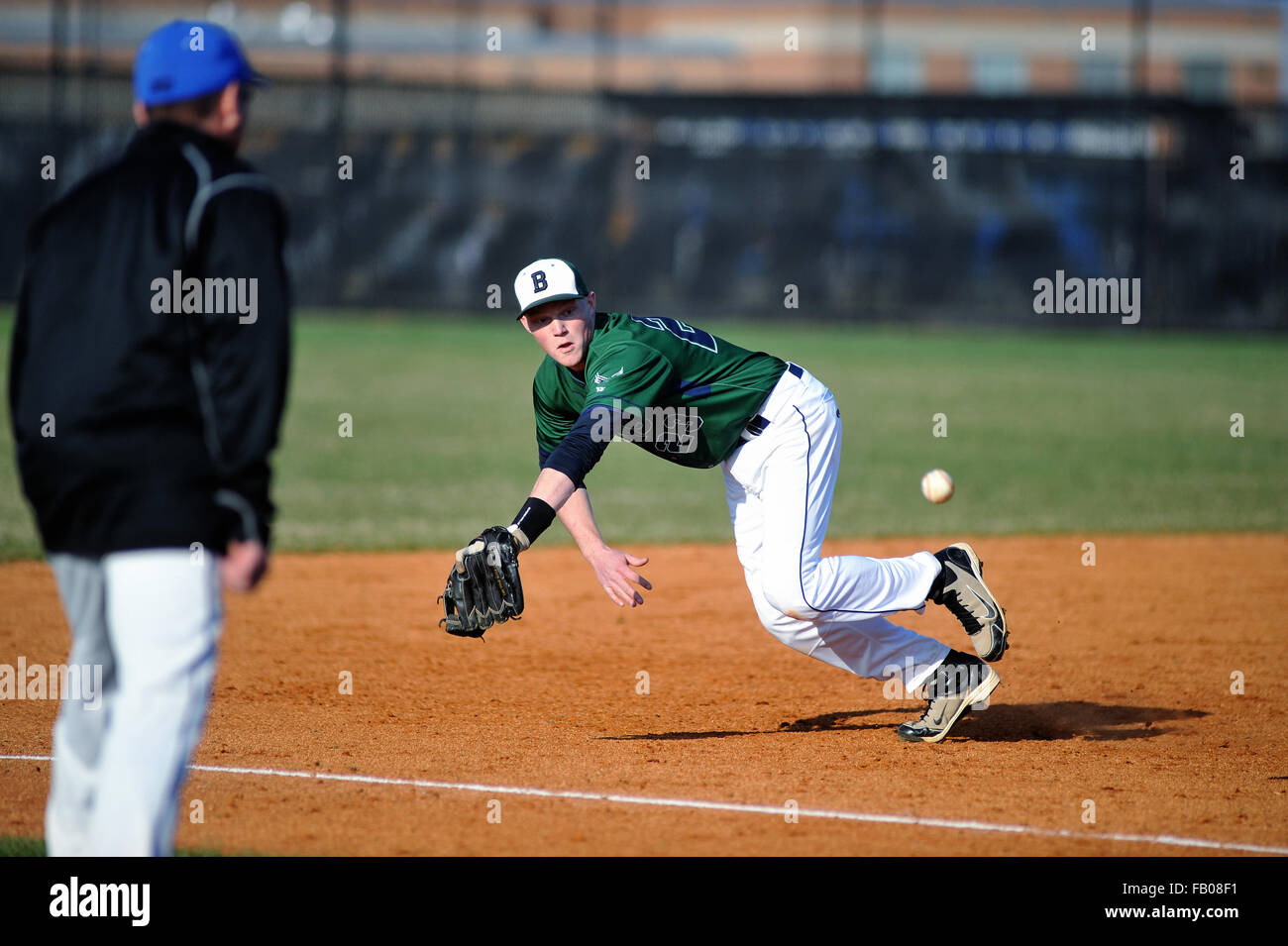 A high school third baseman beginning a dive for a ground ball that wound up down the left field line for a single. USA. Stock Photo