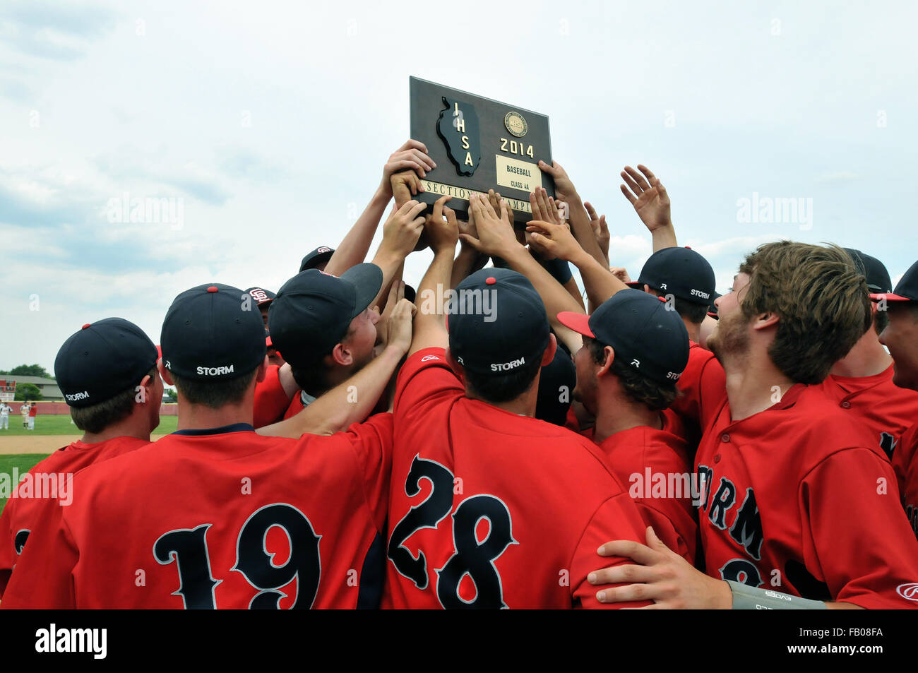 High school baseball team players surround the state sectional title plaque they had just earned on the field moments before. USA. Stock Photo