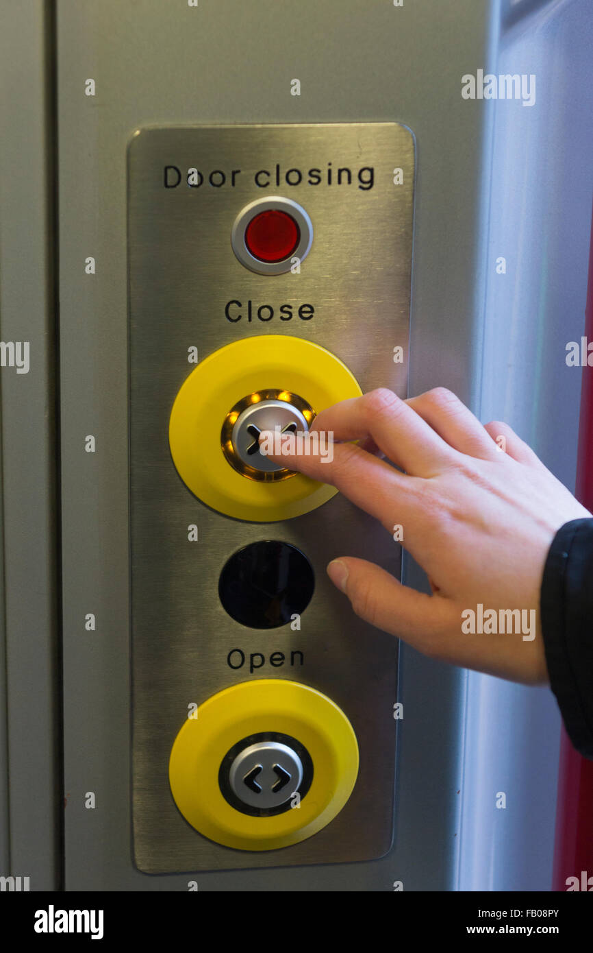 A woman pressing a close door button on a CrossCountry train in England Stock Photo