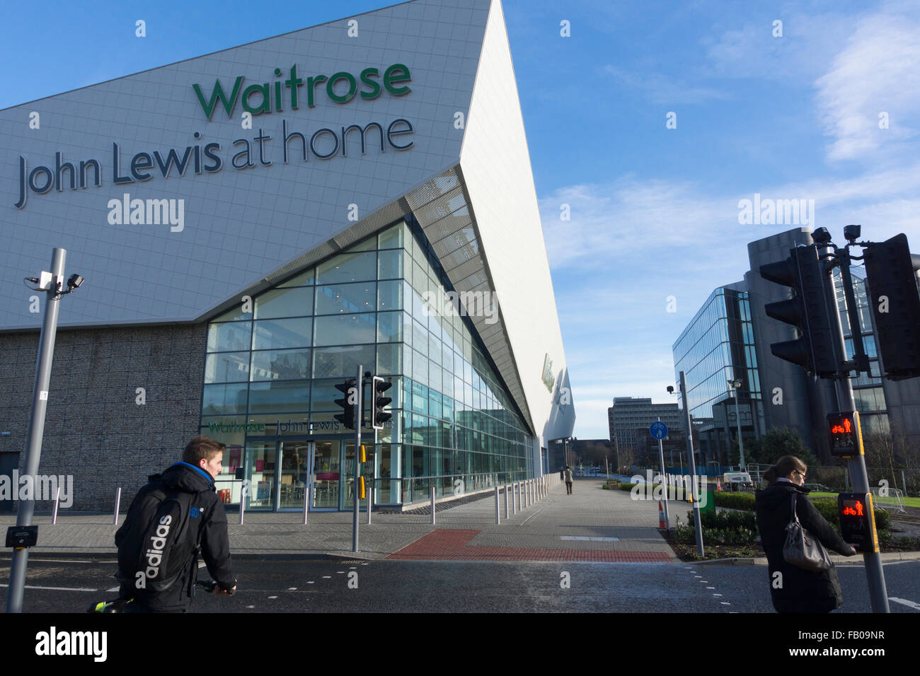 A cyclist and a pedestrian waiting to cross opposite the Waitrose and