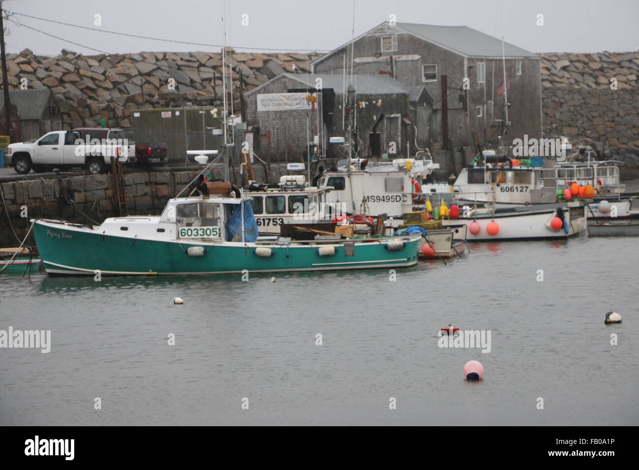 Lobster traps, gear and fishing boats at the pier in Pigeon Cove Harbor
