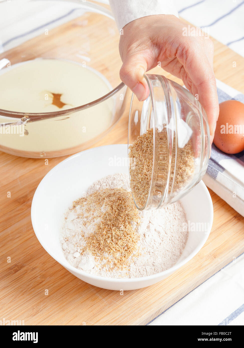 Woman pouring ground flaxseed into flour with baking ingredients for