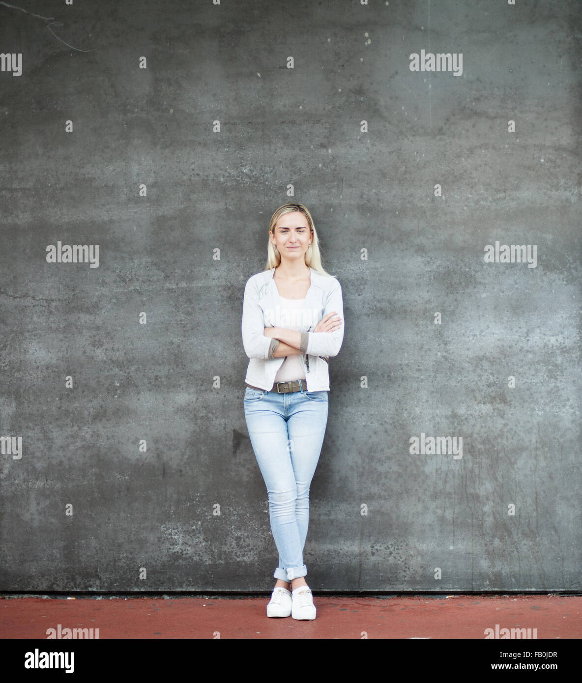 Attractive young woman standing in front of concrete wall Stock Photo