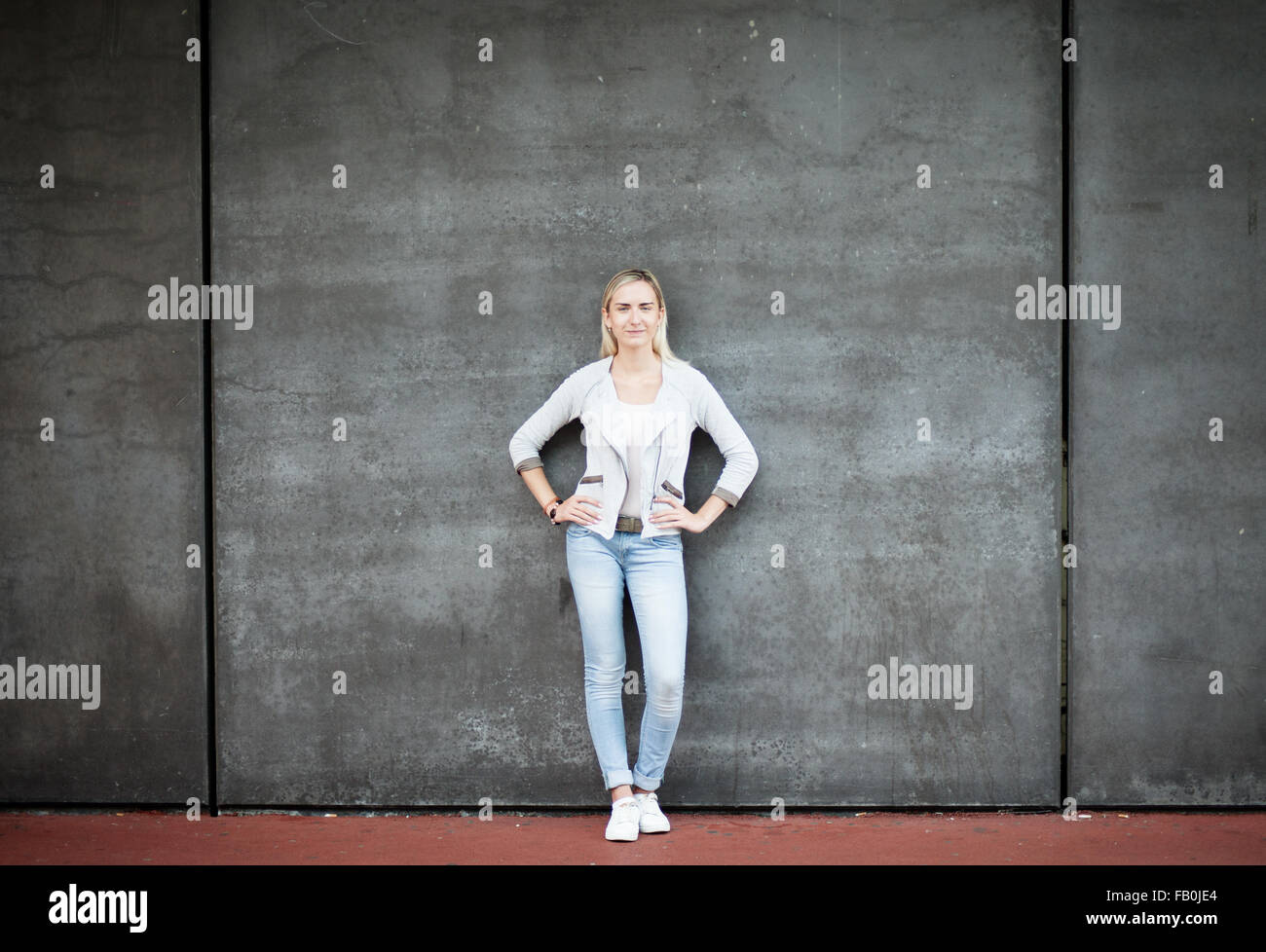 Attractive young woman standing in front of concrete wall Stock Photo