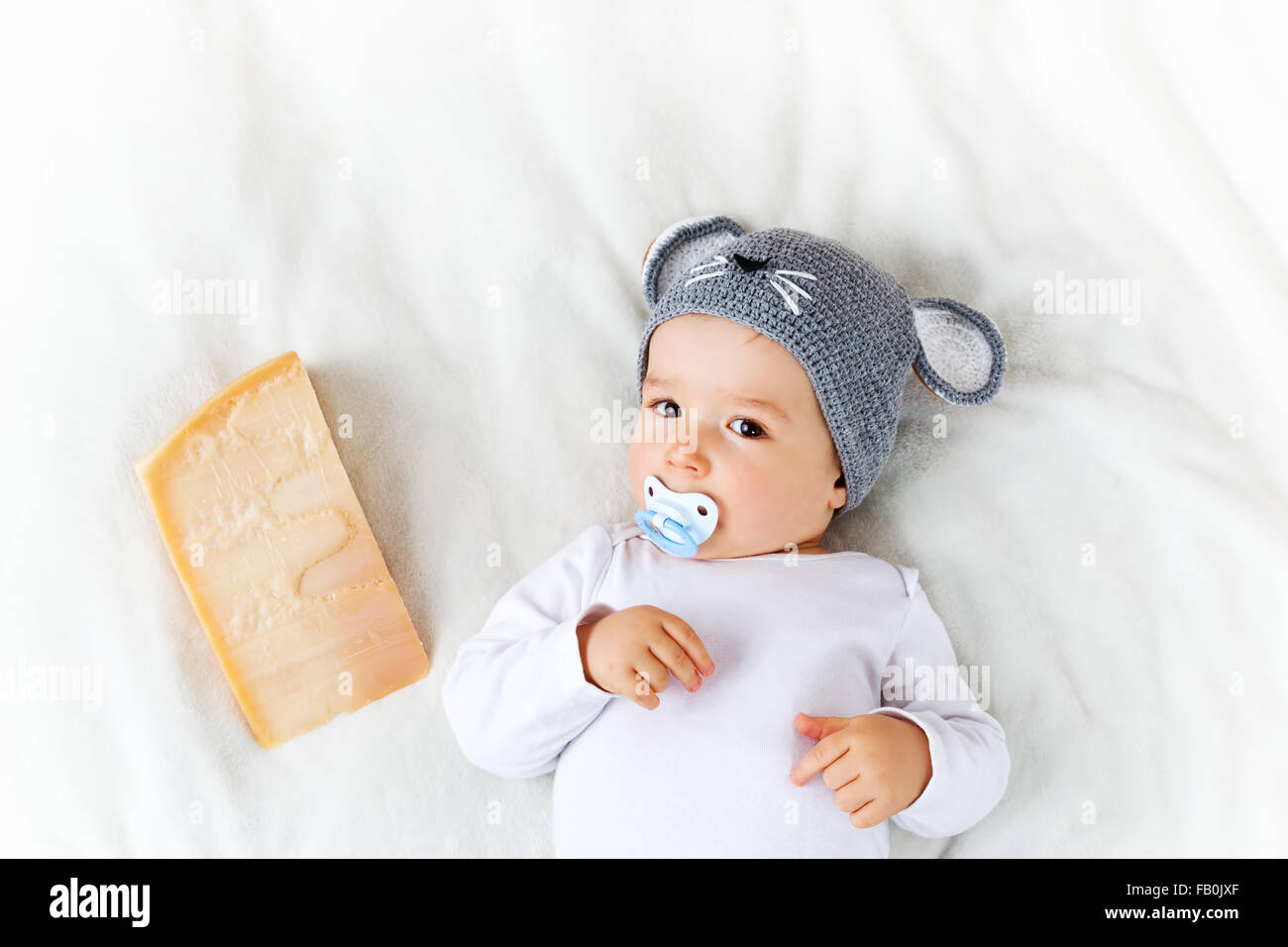 Baby boy in mouse hat lying on blanket with cheese Stock Photo