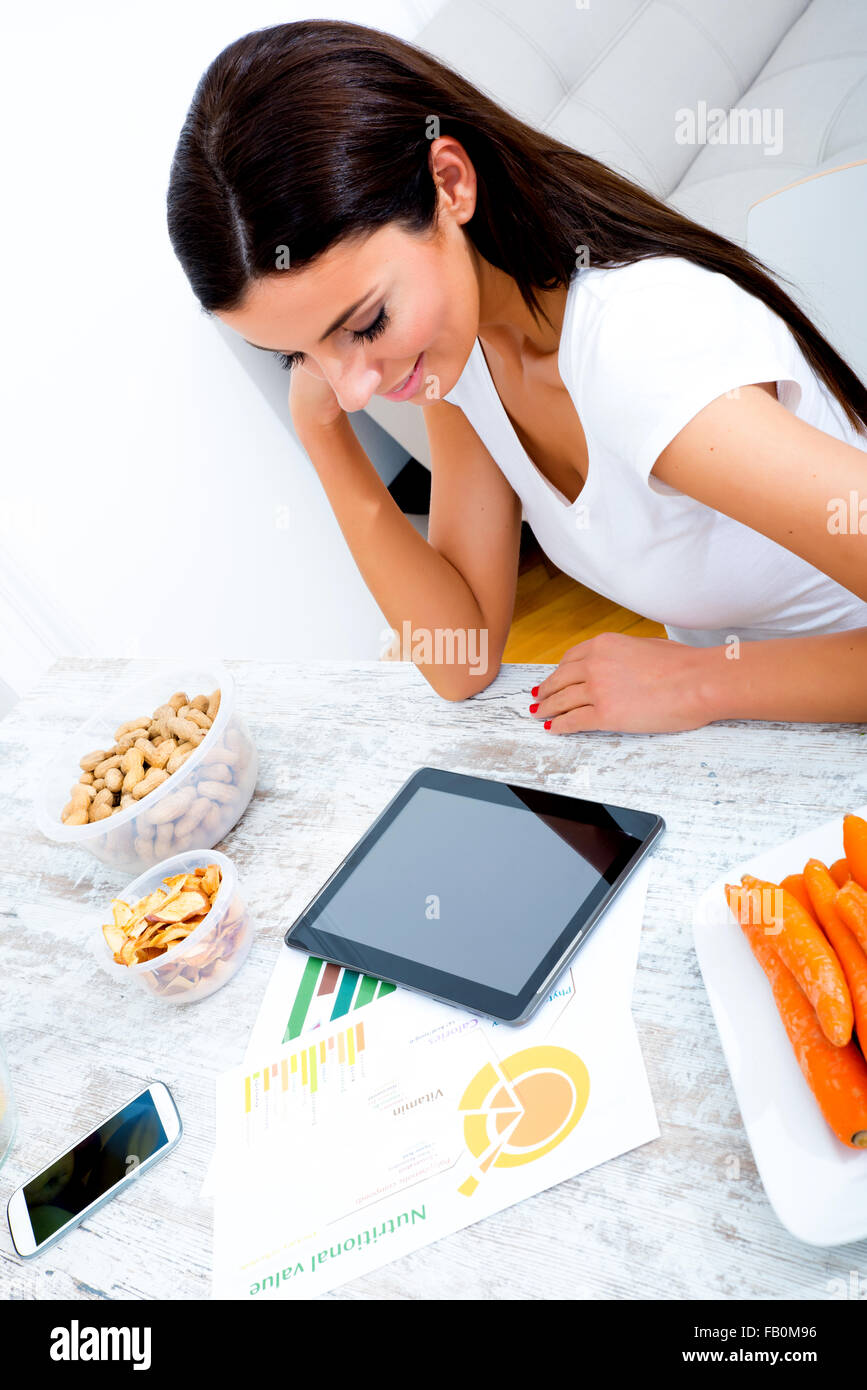 A young beautiful woman using a Tablet computer at home in the kitchen ...