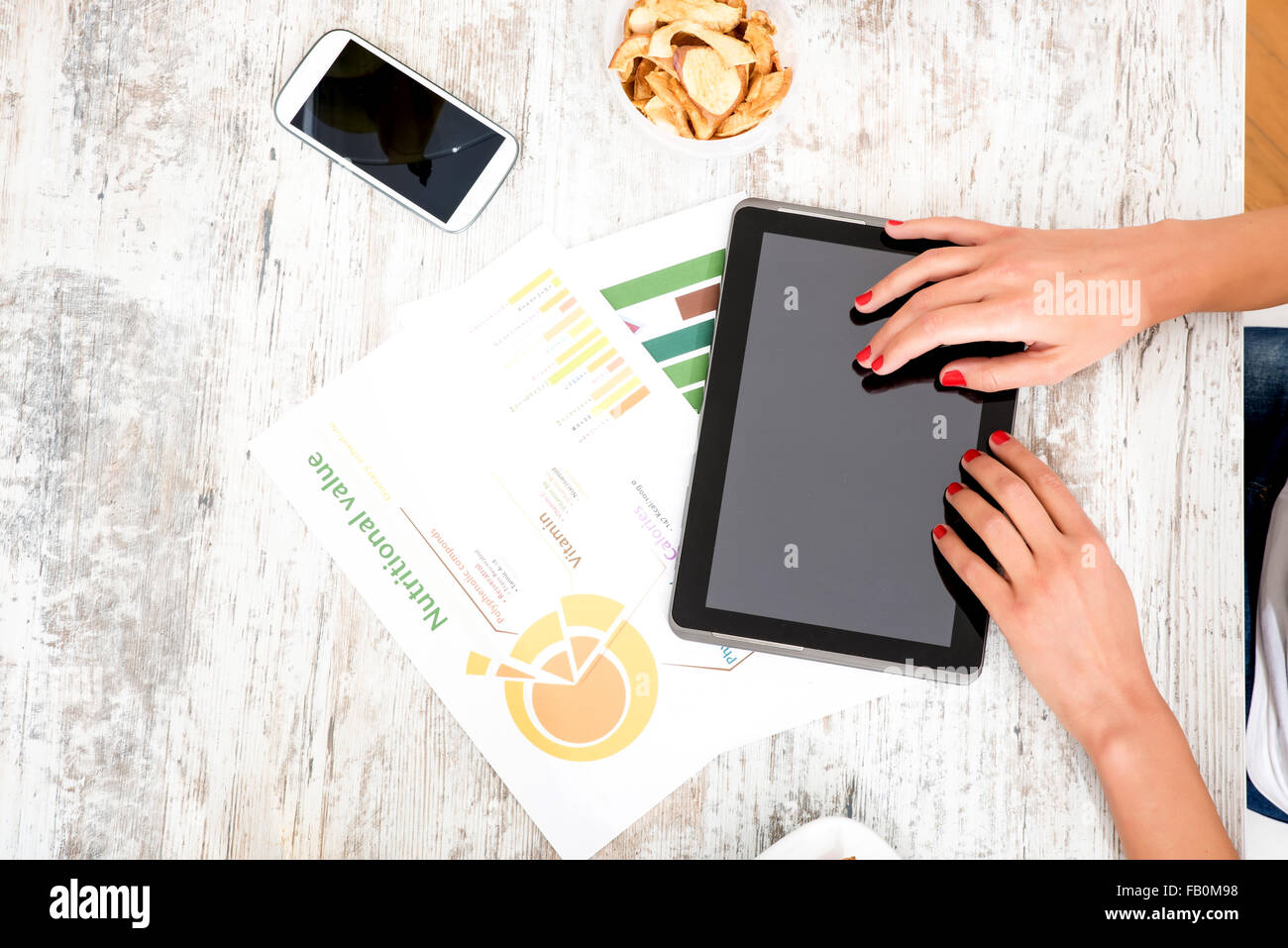 A young beautiful woman using a Tablet computer at home in the kitchen ...
