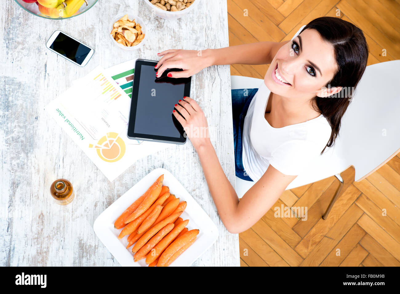 A young beautiful woman using a Tablet computer at home in the kitchen ...