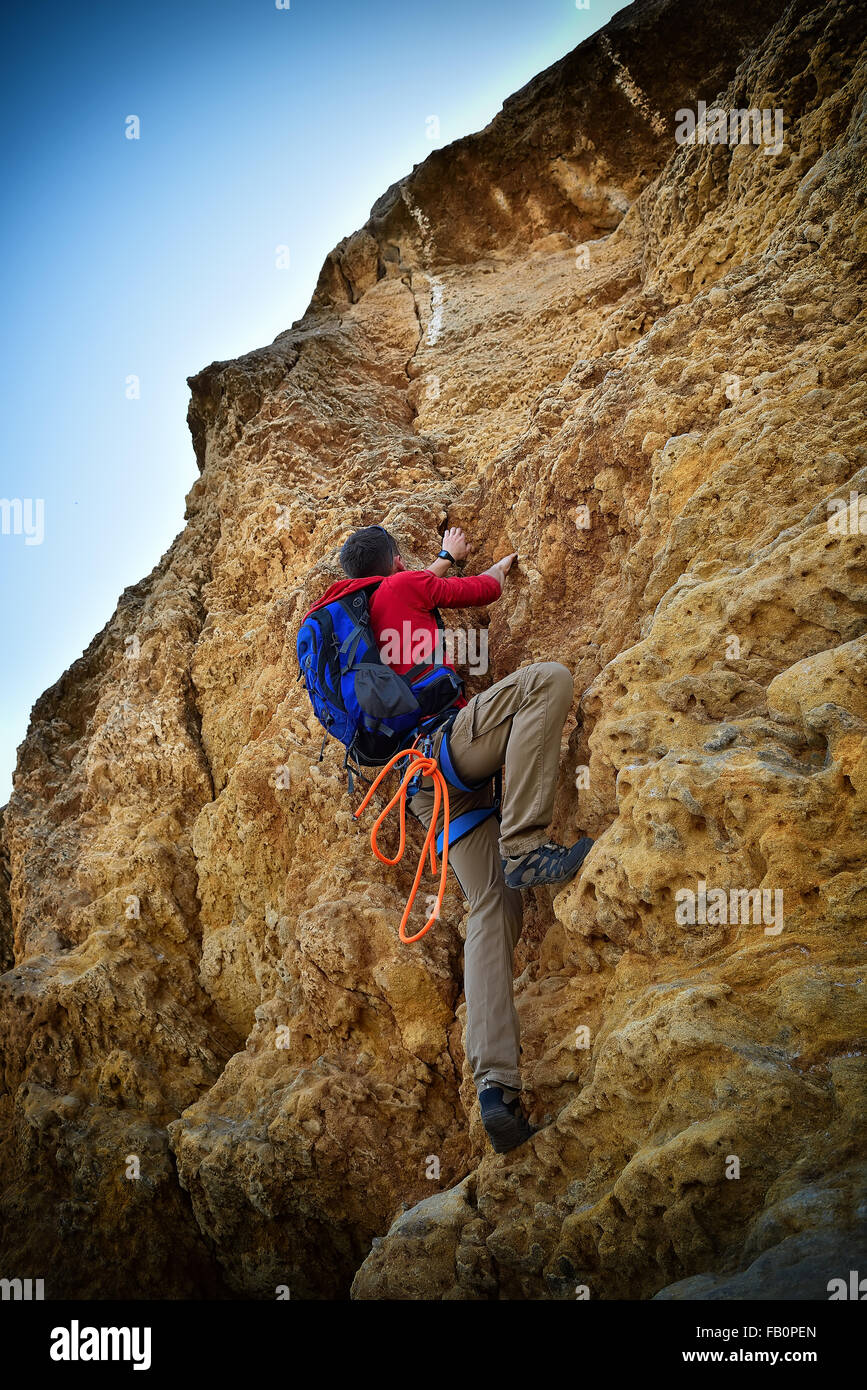 Young man climbing on rock, and blue sky Stock Photo - Alamy