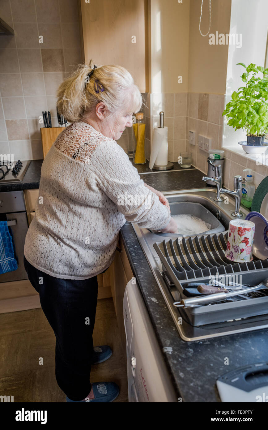 Knit,An Elderly lady in the kitchen washing up Stock Photo