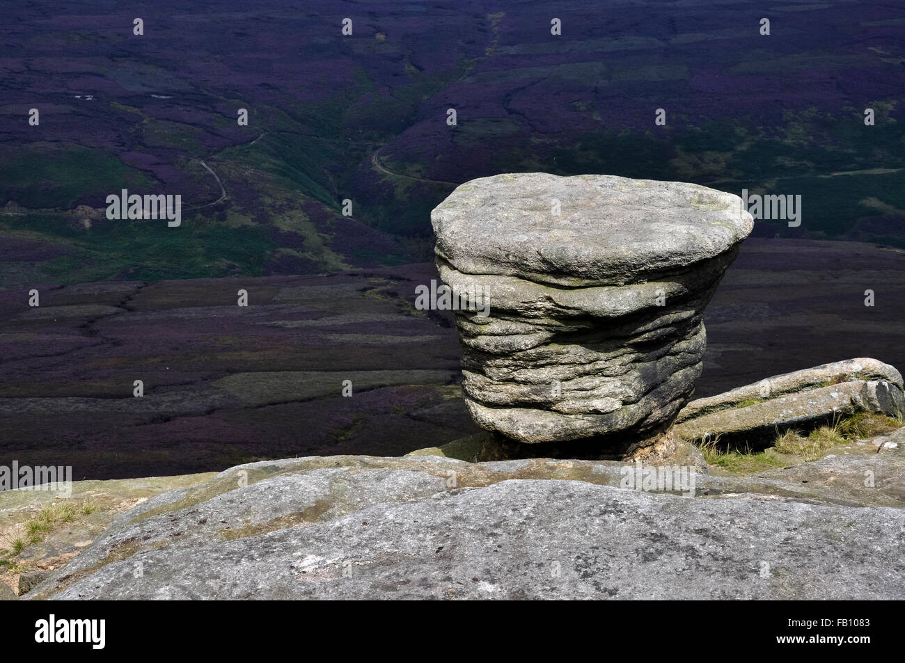 A gritstone feature at Fairbrook Naze in the Peak District, Derbyshire. View of the purple heather moorland beyond. Stock Photo