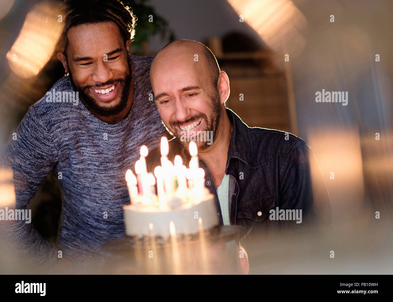 Smiley homosexual couple looking at birthday cake Stock Photo