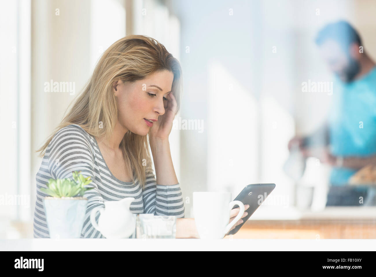 Young woman using tablet and man in background Stock Photo