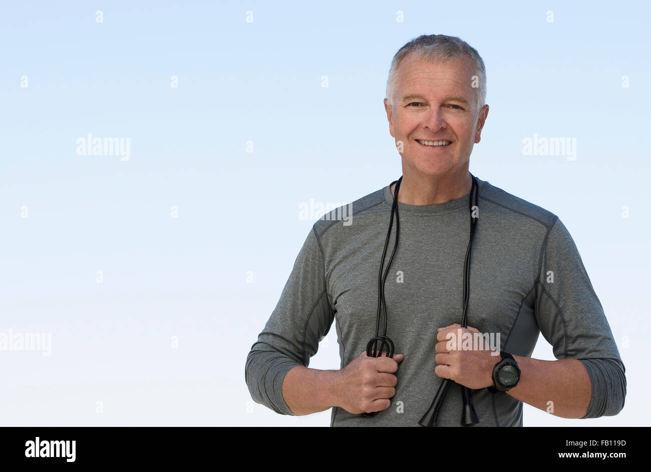 Man with jump rope against clear sky Stock Photo