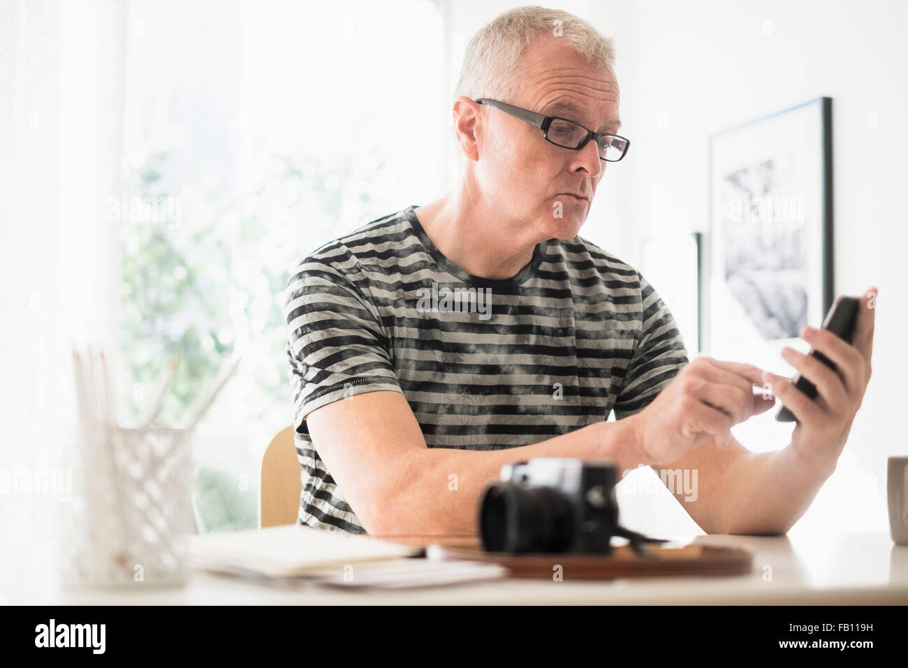 Man in home office using smartphone Stock Photo