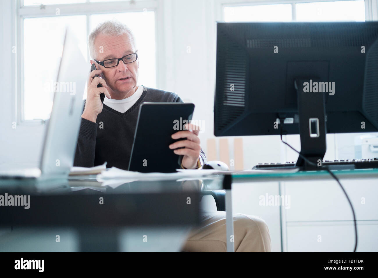 Man in office using smartphone and tablet Stock Photo