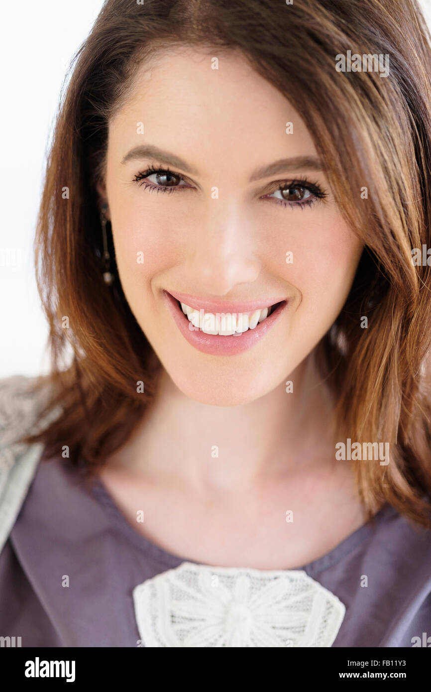 Studio shot portrait of smiling woman with brown hair Stock Photo