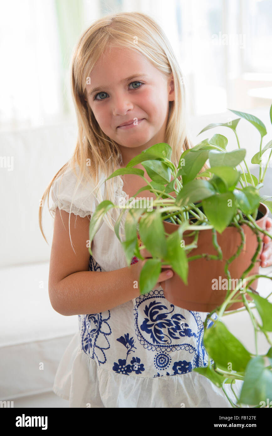 Girl (6-7) holding flower in flower pot Stock Photo - Alamy