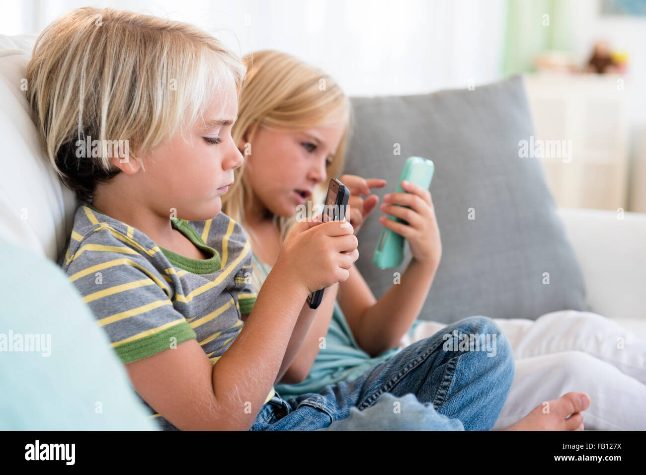 Boy (4-5) and girl (6-7) playing games on smart phones Stock Photo