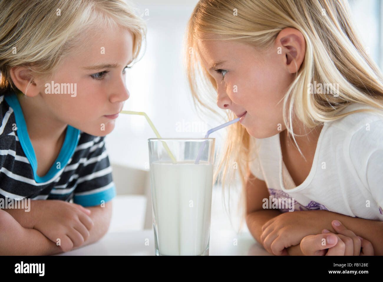 Brother (4-5) with sister (6-7) drinking milk from glass Stock Photo - Alamy