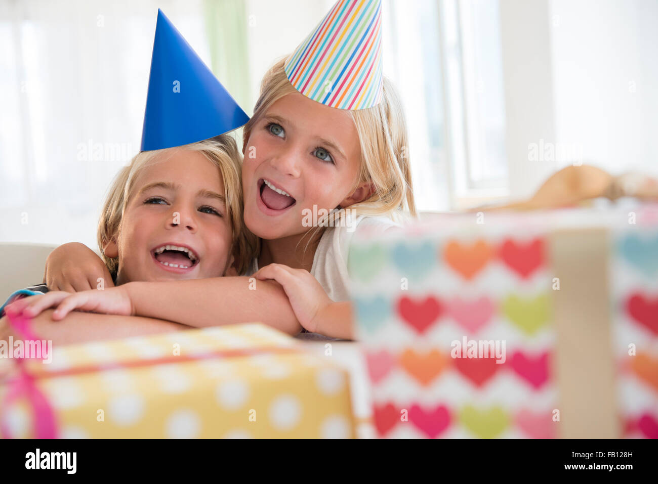 Brother (4-5) and sister (6-7) in embrace at birthday party Stock Photo