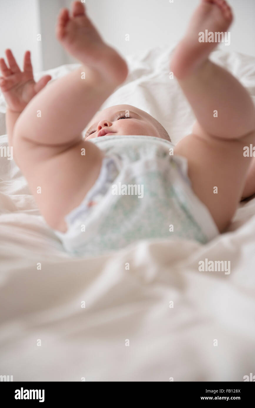 Baby girl (12-17 months) lying down with legs up Stock Photo