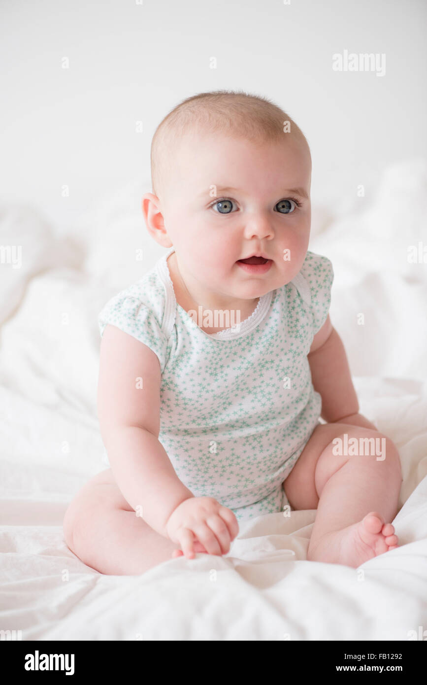 Baby girl (12-17 months) sitting on bed Stock Photo