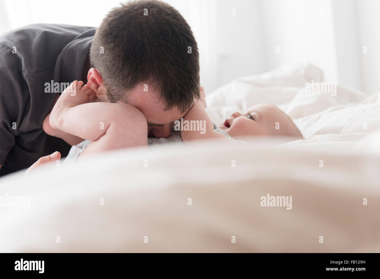 Father kissing baby daughter (12-13 months) belly Stock Photo