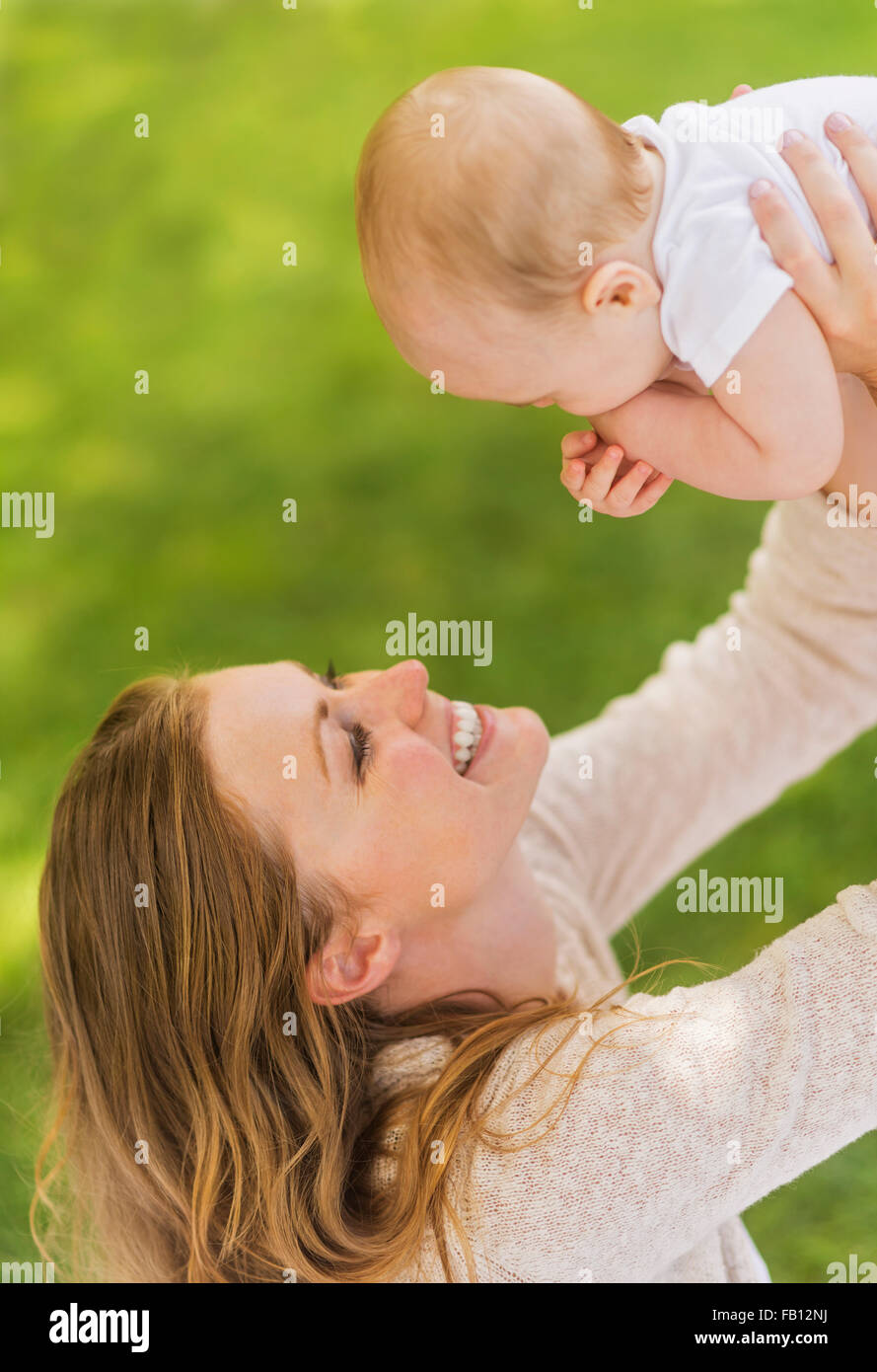 Mother holding up baby boy (6-11 months) Stock Photo